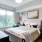 Model bedroom at our apartments for rent in Fairfax, VA, featuring a queen bed and windows with curtains.